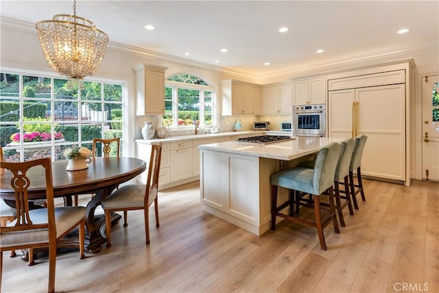 kitchen with stainless steel appliances, decorative backsplash, pendant lighting, a center island, and ornamental molding