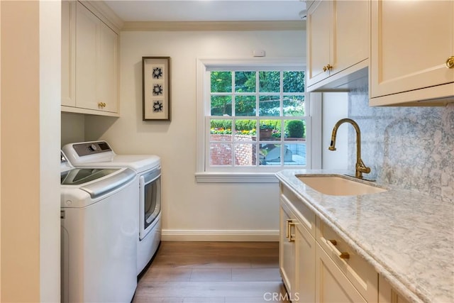 washroom featuring sink, cabinets, washer and dryer, and light hardwood / wood-style flooring