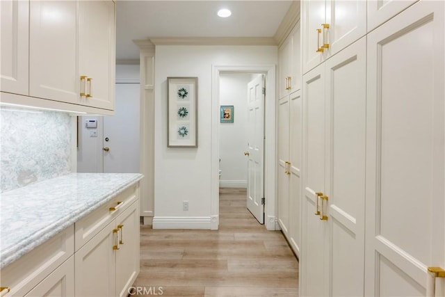 interior space with light wood-type flooring, crown molding, and decorative backsplash