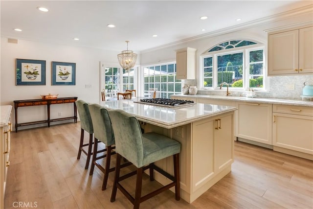 kitchen with a center island, pendant lighting, a baseboard radiator, stainless steel gas stovetop, and tasteful backsplash