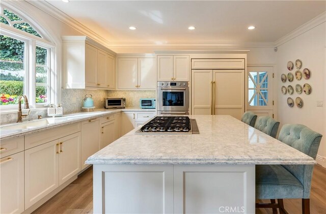 kitchen with appliances with stainless steel finishes, light stone countertops, a breakfast bar, and a center island