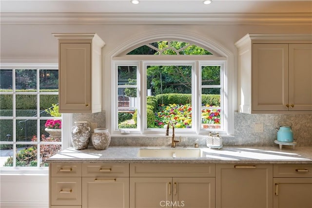 kitchen with crown molding, sink, cream cabinets, and decorative backsplash