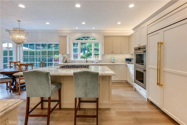 kitchen with stainless steel appliances, a kitchen island, tasteful backsplash, light stone counters, and pendant lighting