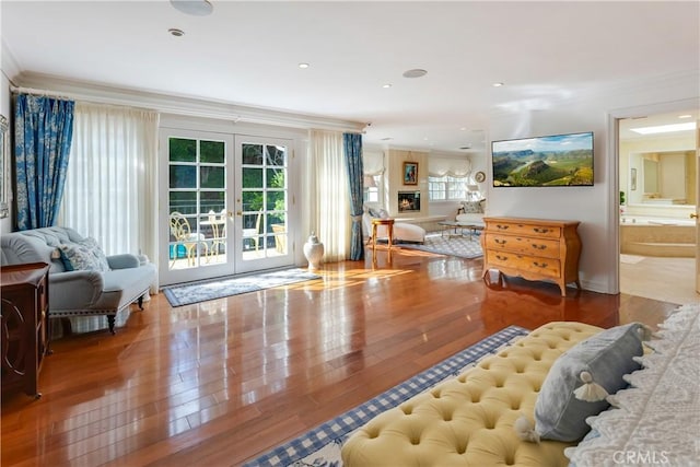 living area featuring wood-type flooring, french doors, and crown molding