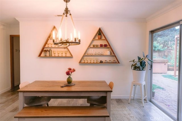 dining area with ornamental molding, a notable chandelier, and light hardwood / wood-style flooring