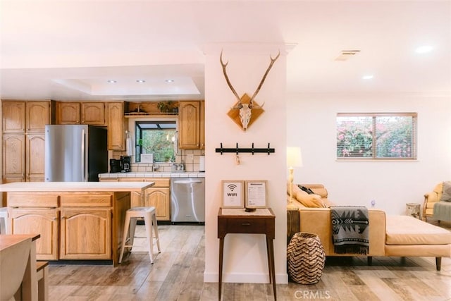 kitchen with a kitchen bar, light hardwood / wood-style floors, a center island, and appliances with stainless steel finishes