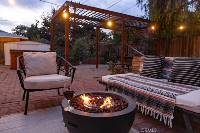 patio terrace at dusk with a wooden deck, a pergola, a hot tub, and an outdoor fire pit