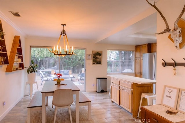 dining area featuring an inviting chandelier, crown molding, light hardwood / wood-style flooring, and a wealth of natural light