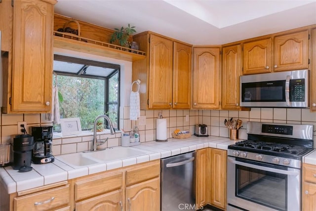 kitchen featuring stainless steel appliances, sink, tile countertops, and decorative backsplash