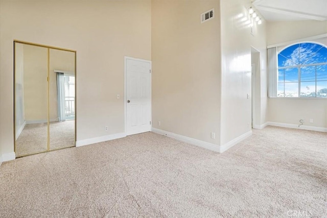 carpeted empty room with a wealth of natural light and high vaulted ceiling