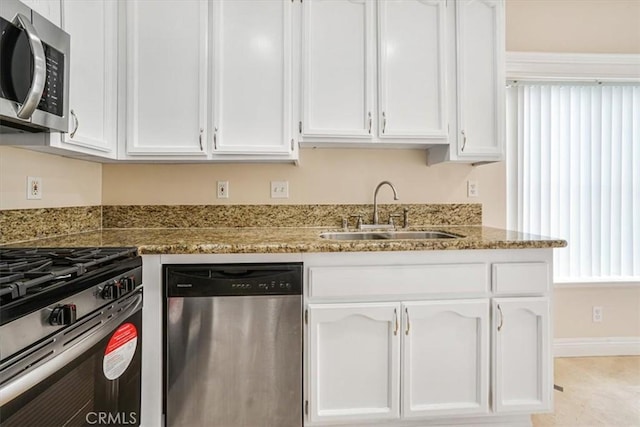 kitchen featuring white cabinetry, appliances with stainless steel finishes, sink, and light stone counters