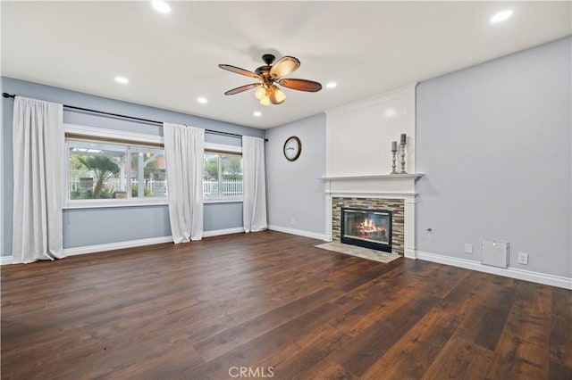 unfurnished living room featuring dark wood-type flooring, ceiling fan, and a fireplace