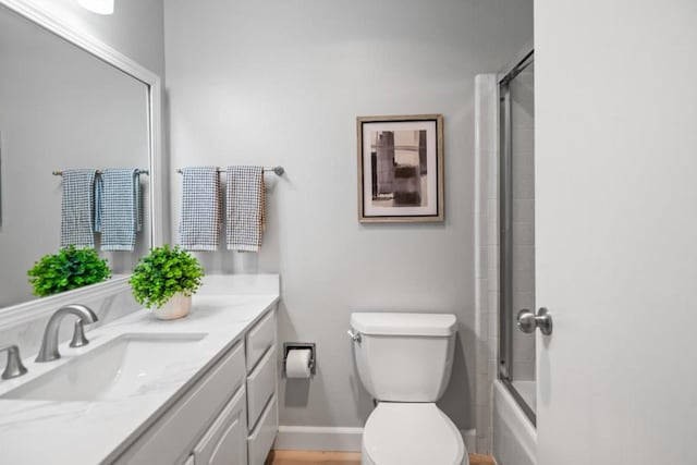 full bathroom featuring enclosed tub / shower combo, vanity, and toilet