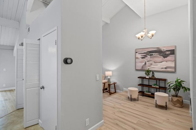 hall with vaulted ceiling with beams, an inviting chandelier, and light wood-type flooring