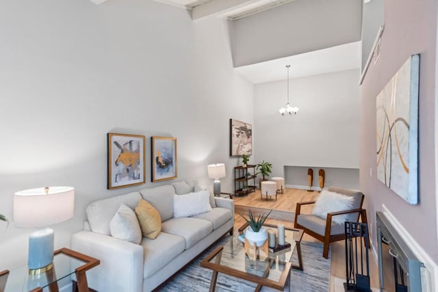 living room with an inviting chandelier, beam ceiling, hardwood / wood-style floors, and a high ceiling