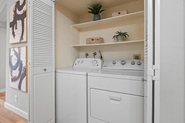 washroom with washing machine and dryer and light hardwood / wood-style floors