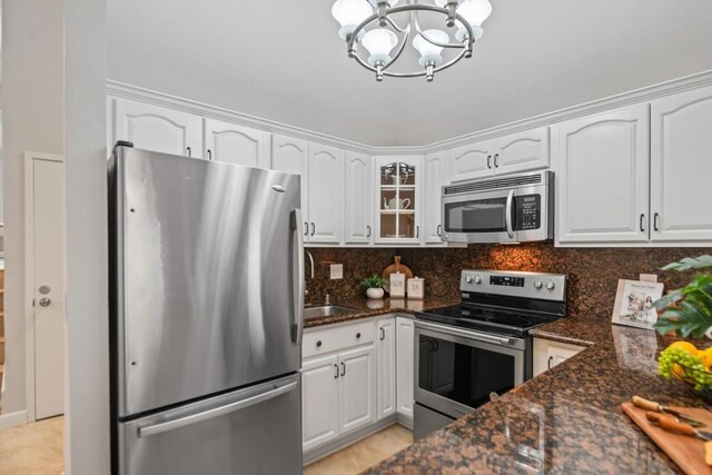 kitchen with tasteful backsplash, appliances with stainless steel finishes, white cabinets, and dark stone counters