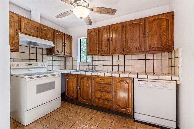 kitchen featuring sink, white appliances, ceiling fan, tasteful backsplash, and tile counters