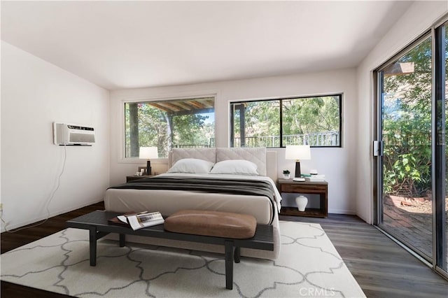 bedroom featuring multiple windows, access to exterior, dark hardwood / wood-style floors, and an AC wall unit