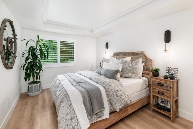 bedroom featuring a tray ceiling and light hardwood / wood-style floors