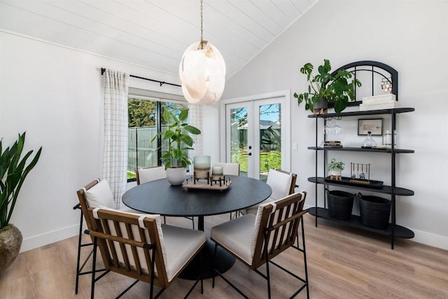 dining area featuring vaulted ceiling, light hardwood / wood-style floors, french doors, and a healthy amount of sunlight