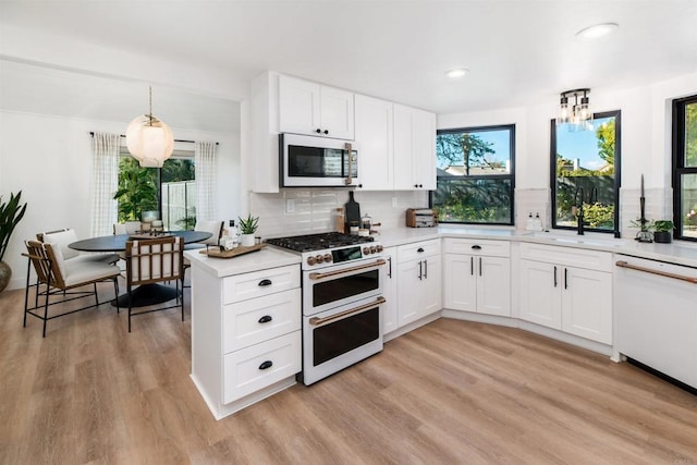 kitchen with white cabinetry, white appliances, hanging light fixtures, and light wood-type flooring