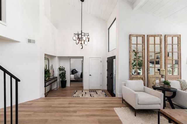 entrance foyer with vaulted ceiling with beams, an inviting chandelier, wooden ceiling, and light wood-type flooring