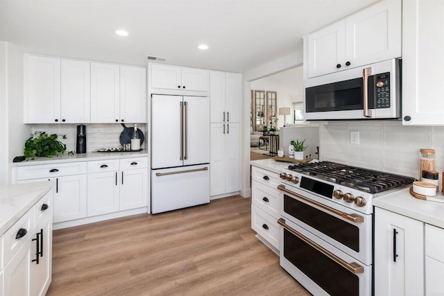 kitchen featuring high end appliances, white cabinets, and light wood-type flooring