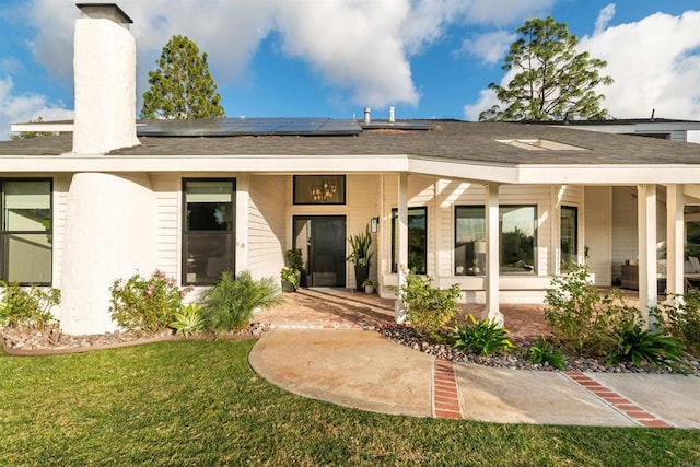 back of property with a lawn and solar panels