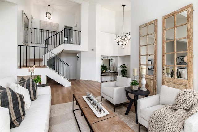 living room with a notable chandelier, hardwood / wood-style flooring, and a high ceiling