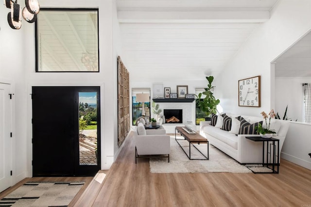 living room featuring lofted ceiling with beams, a fireplace, and light hardwood / wood-style floors