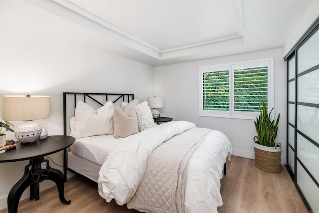 bedroom with hardwood / wood-style flooring and a raised ceiling