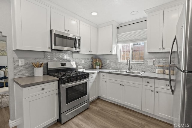 kitchen featuring sink, appliances with stainless steel finishes, backsplash, white cabinets, and light wood-type flooring