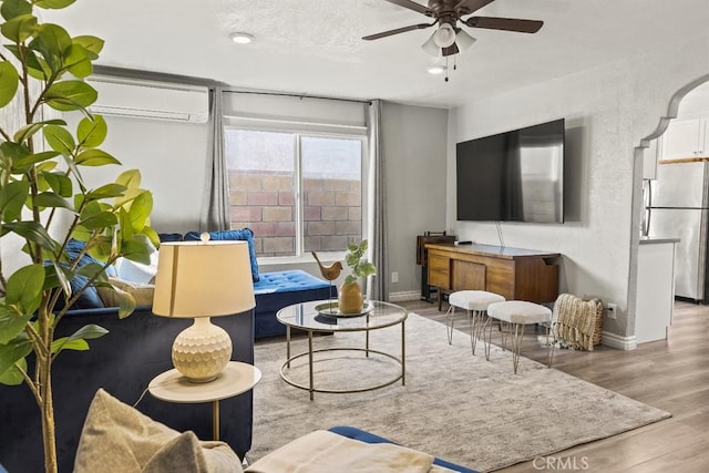 living room featuring ceiling fan, light hardwood / wood-style floors, and a wall mounted AC