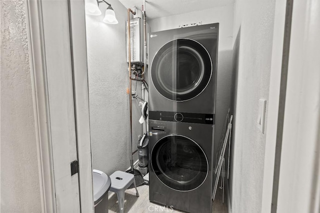 clothes washing area with stacked washing maching and dryer