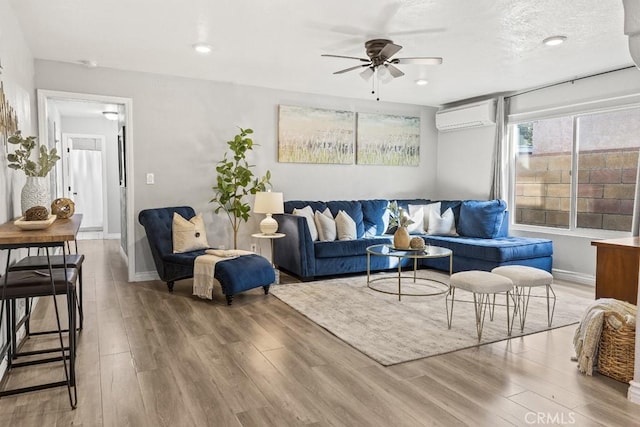 living room with ceiling fan, a wall mounted air conditioner, and wood-type flooring