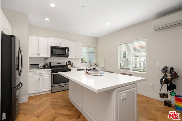 kitchen featuring stainless steel gas range, black fridge, white cabinetry, a center island, and light parquet flooring