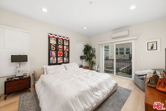 bedroom featuring a wall mounted air conditioner, access to exterior, and light wood-type flooring