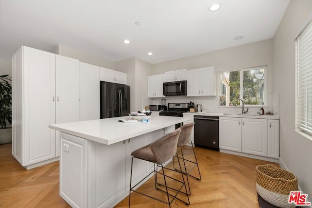 kitchen with a kitchen island, white cabinetry, sink, light parquet floors, and black appliances