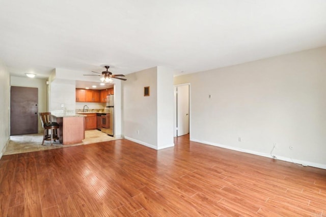 unfurnished living room with ceiling fan and light hardwood / wood-style flooring