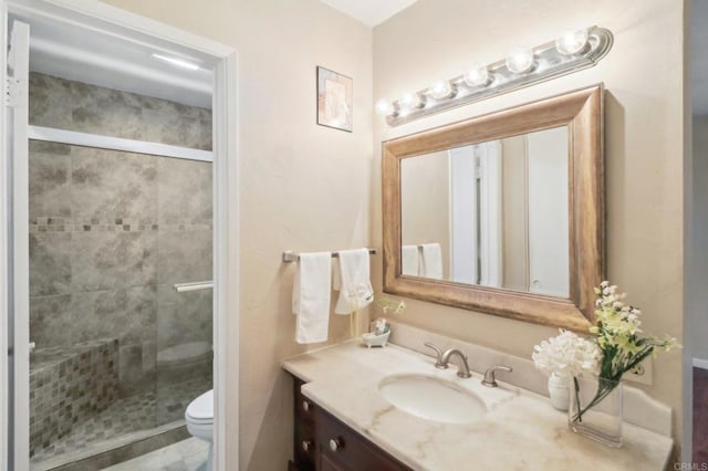 bathroom featuring a shower with door, vanity, and toilet