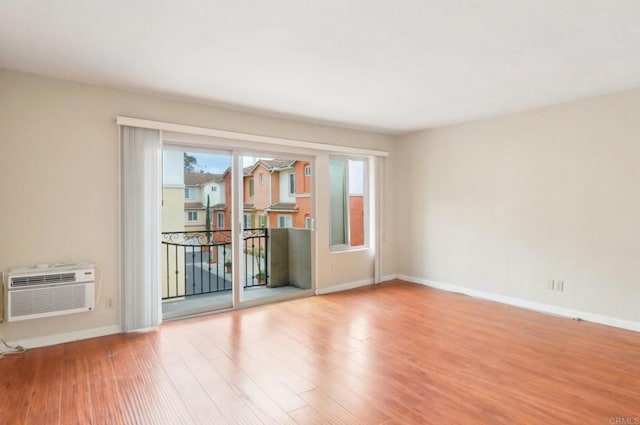 empty room with a wall mounted air conditioner and light hardwood / wood-style flooring