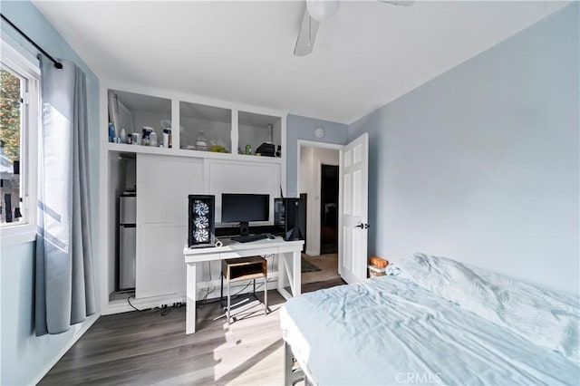 bedroom with hardwood / wood-style flooring, ceiling fan, and stainless steel refrigerator