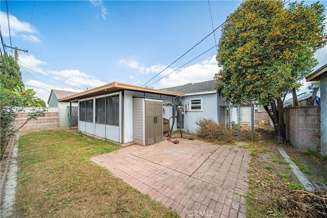 rear view of house featuring a yard, a sunroom, and a patio area