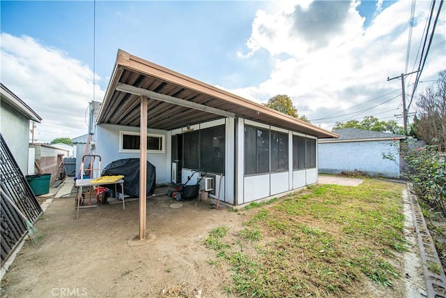 back of property with a lawn and a sunroom