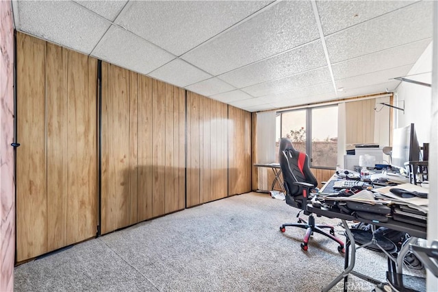 carpeted office space with wooden walls and a drop ceiling