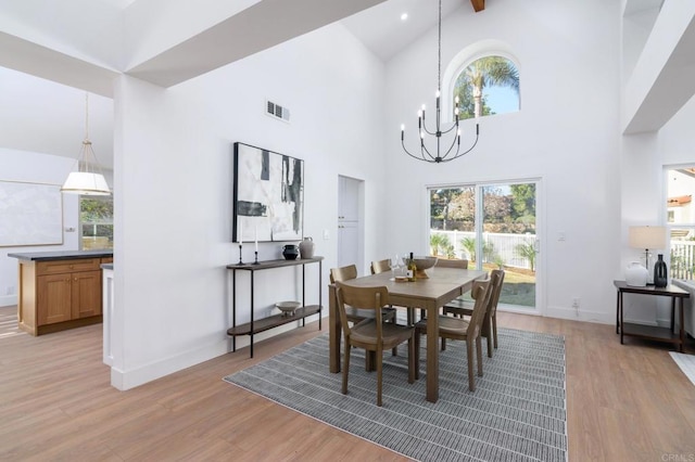 dining space featuring an inviting chandelier, light hardwood / wood-style flooring, and high vaulted ceiling