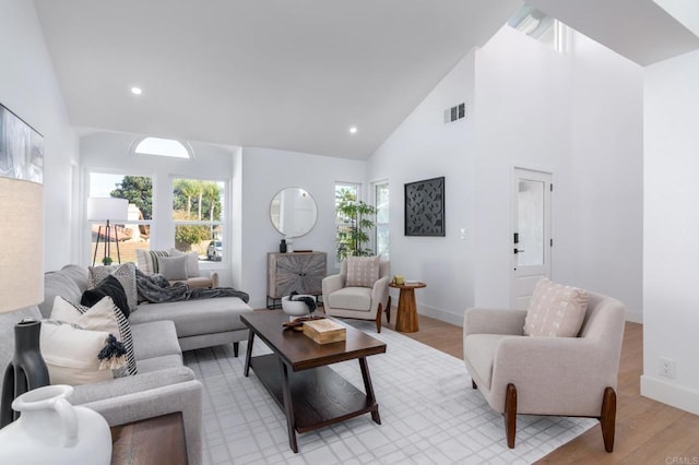 living room featuring high vaulted ceiling, a healthy amount of sunlight, and light hardwood / wood-style floors