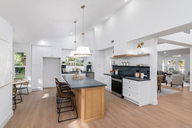 kitchen featuring white cabinetry, a center island, light wood-type flooring, appliances with stainless steel finishes, and pendant lighting