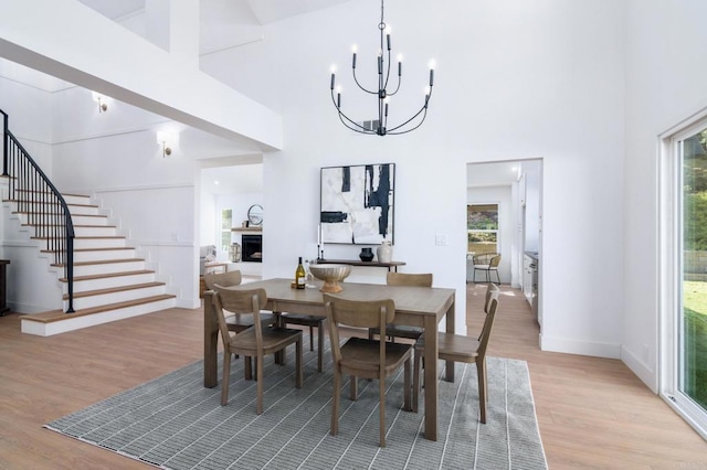 dining space featuring a towering ceiling, plenty of natural light, light hardwood / wood-style floors, and a chandelier